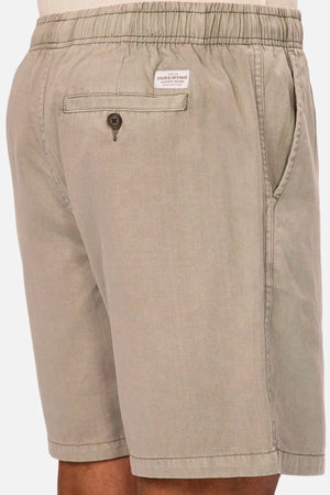 A close-up of a person wearing the Industrie The Dublin Short—men's cotton-linen summer shorts with an elastic waistband, side pockets, and a back pocket featuring a button and a white label above it.