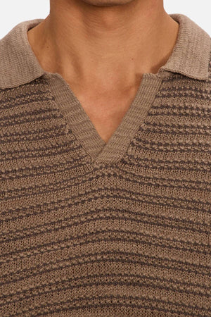 Close-up of a person wearing Industrie The Matera Polo, a heavyweight knit with horizontal textured stripes and a V-neck collar. Only the upper chest and neck are shown; the face is cropped out.
