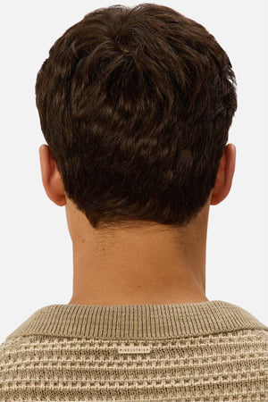 A person with short, dark brown hair is seen from behind wearing a light beige Industrie The Matera Polo, made from 100% cotton heavyweight knitted fabric, featuring a small INDUSTRIE label at the collar. The background is plain and light.