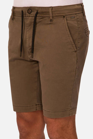 A person wearing Industrie The New Drifter Cuba Short in brown, knee-length with side and back pockets, styled with a white top. The image highlights the slim fit from waist to above the knees—ideal as men's everyday shorts.