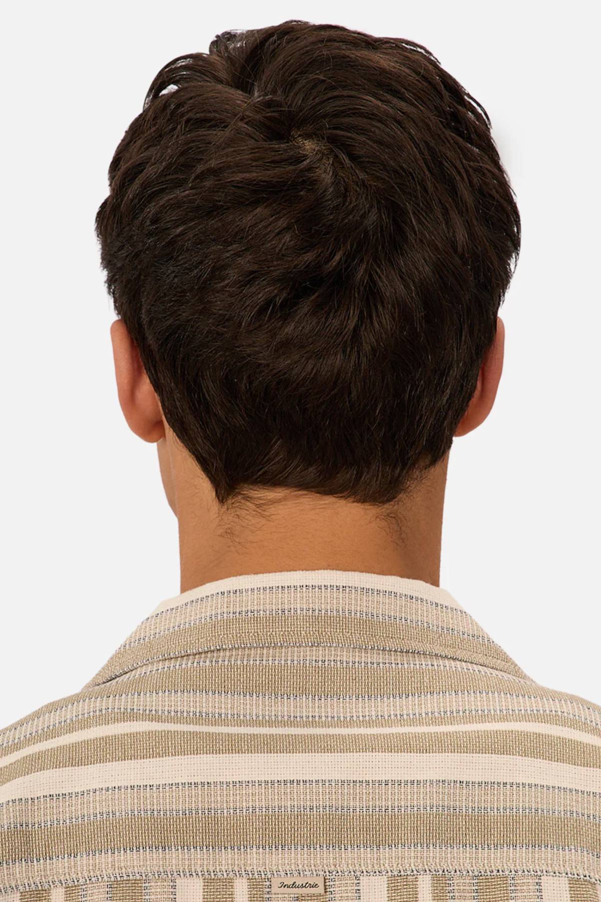 A person with short, dark brown hair is seen from behind wearing the Industrie The Textured Livorno Short Sleeve Shirt in beige and white stripes. The relaxed fit shirt stands out against a plain, light-colored background.