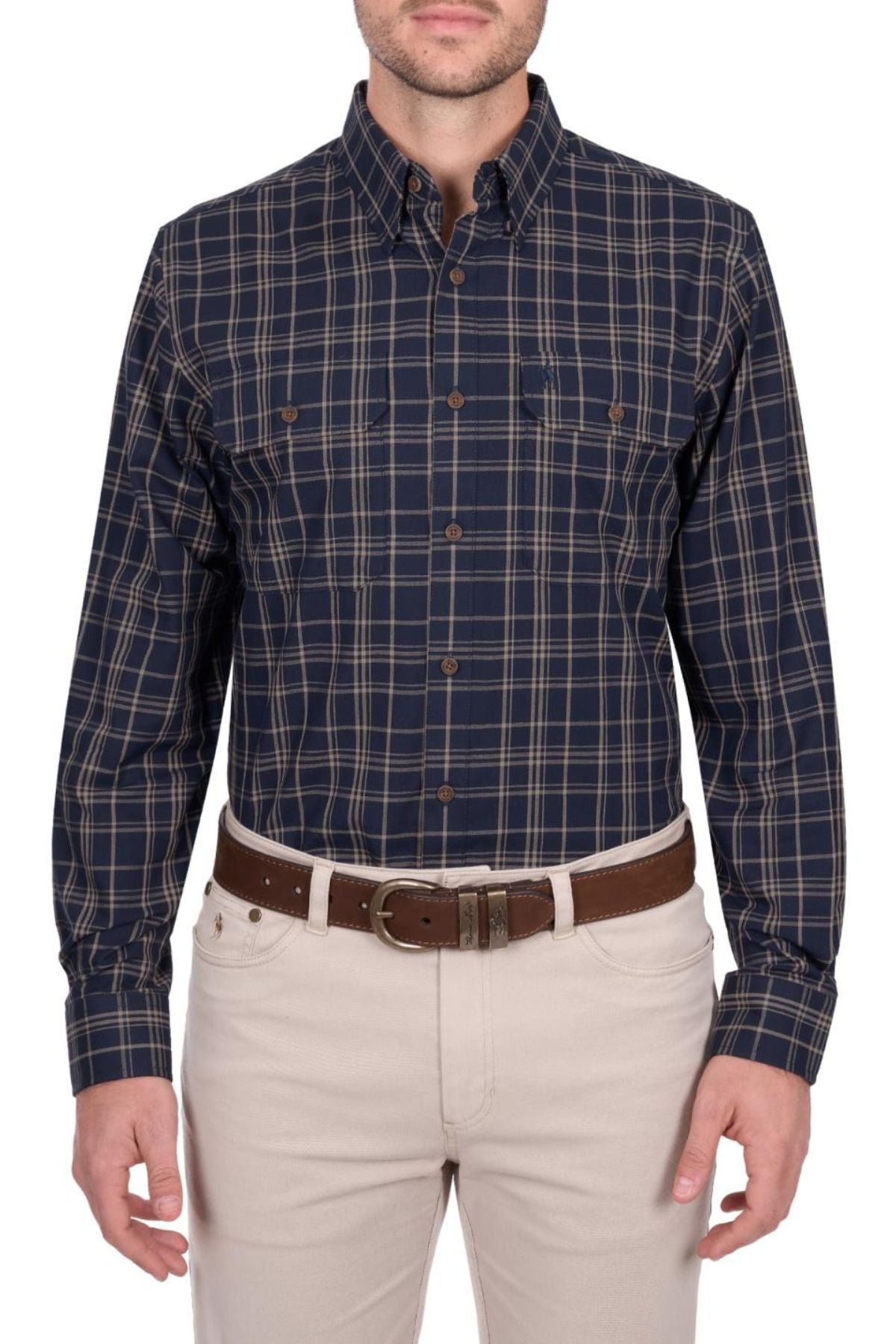 A man wears the Thomas Cook Adam Shirt—navy blue and tan plaid, 100% cotton, long sleeves—with light beige pants and a brown belt. The photo shows him from shoulders to mid-thigh, facing forward.