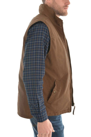 A man wearing a blue plaid shirt and the Thomas Cook Canvas Vest with sherpa lining stands sideways against a white background.