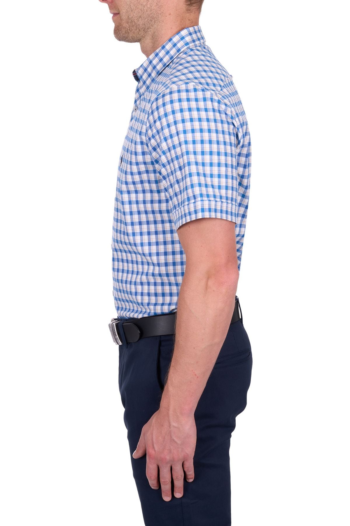 A man stands in profile wearing the Thomas Cook Chris Tailored Short Sleeve Shirt with blue and white checks, paired with dark navy pants and a black belt, set against a plain white background.