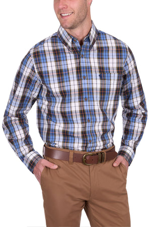 Smiling man wears the Thomas Cook Daniel Shirt, a blue, white, and black yarn dyed check long-sleeve shirt, paired with khaki pants and a brown belt, standing with one hand in his pocket.