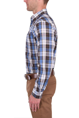 A man in profile wears the Thomas Cook Daniel Shirt, a blue, black, and white yarn-dyed checked long-sleeve shirt tucked into brown pants with a brown belt, standing against a white background.