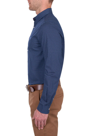 A man in profile wears the Thomas Cook David Tailored Shirt—navy blue with a small white dot geometric print—paired with tan pants and a brown belt, set against a white background.