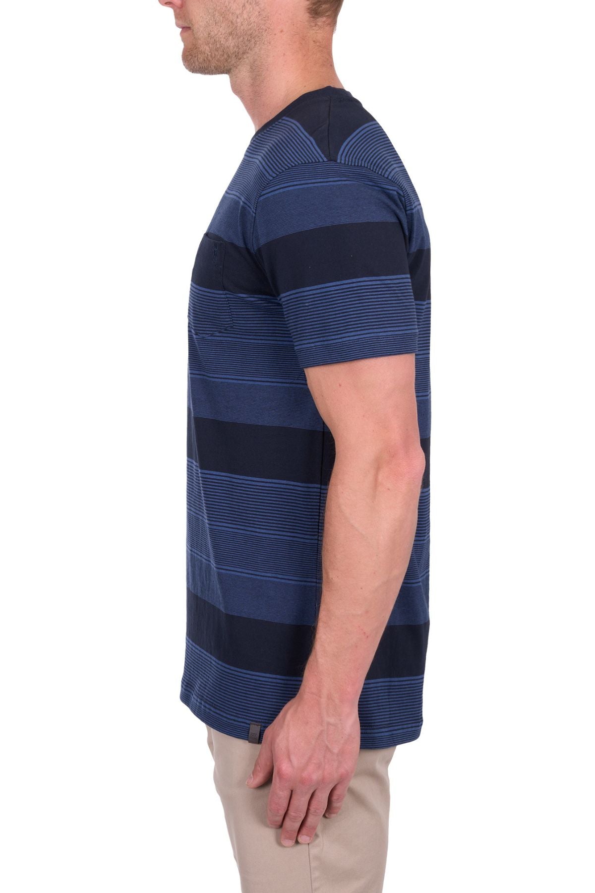 A man in the Thomas Cook Edward Tee, a 100% cotton jersey with navy and dark blue stripes, paired with beige pants, stands in profile facing left against a white background.