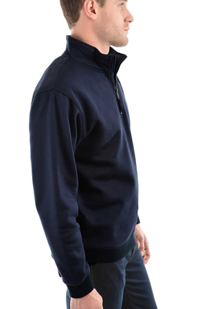 A man in a Thomas Cook Flinders Fleece Top, navy blue with a quarter zip, and dark pants stands in profile against a white background.