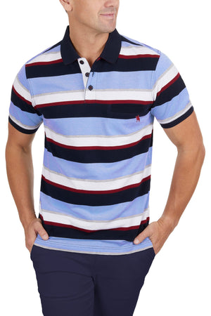 A man wears the Thomas Cook Gavin Polo, a 100% cotton shirt with blue, white, red, and navy stripes, paired with navy pants and his hands in his pockets against a white background.