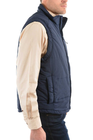 A man in a light beige long-sleeve shirt, dark jeans, and a navy Thomas Cook Hawkesbury River Vest with polar fleece-lined pockets is shown from the side against a white background.