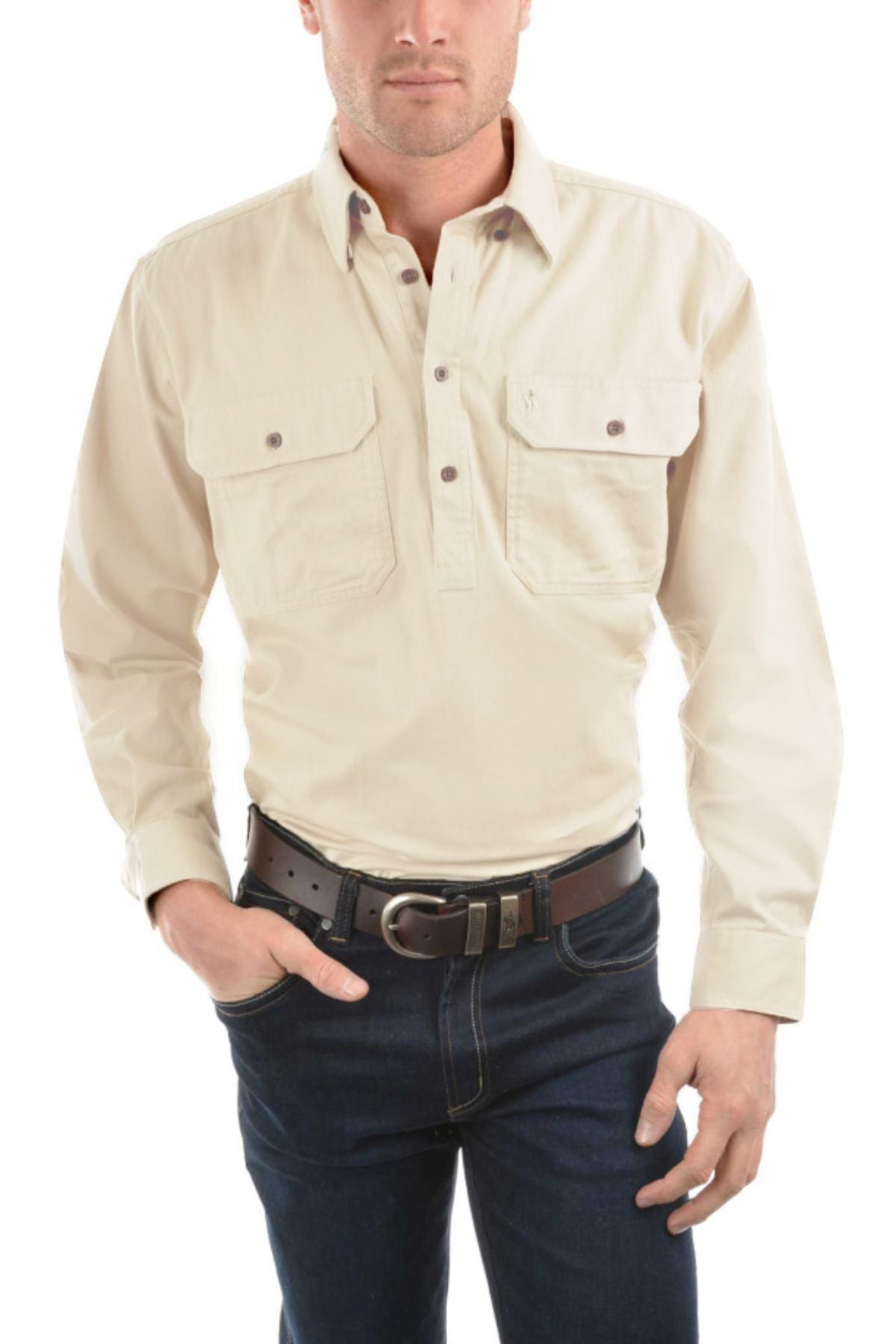 A man wears the Thomas Cook Heavy Drill Half Placket Shirt in light beige, featuring two chest pockets, paired with dark blue jeans and a dark brown belt. He stands against a white background with one hand in his pocket.