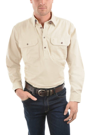 A man wears the Thomas Cook Heavy Drill Half Placket Shirt in light beige, featuring two chest pockets, paired with dark blue jeans and a dark brown belt. He stands against a white background with one hand in his pocket.