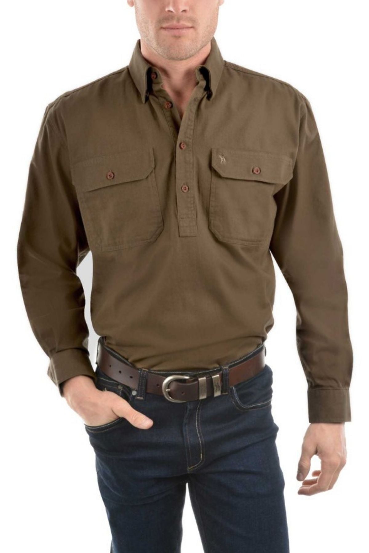 A man wearing a Thomas Cook Heavy Drill Half Placket Shirt with countryman pockets, dark blue jeans, and a brown belt stands with one hand in his pocket.