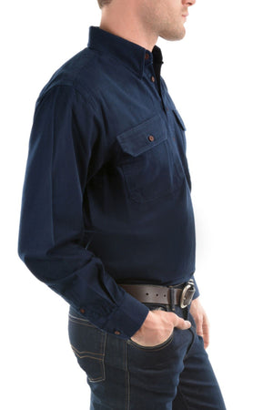 A man stands in side profile wearing the Thomas Cook Heavy Drill Half Placket Shirt in dark blue with front pockets and dark jeans, one hand in his pocket and the other by his side.