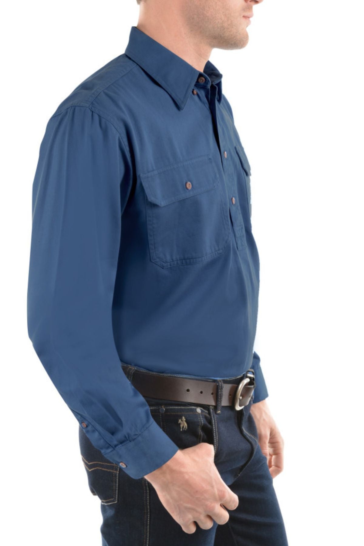 A man shown from the side against a white background wears the Thomas Cook Heavy Drill Half Placket Shirt in blue, paired with dark jeans and a black belt with a large silver buckle. His face is partially out of view.