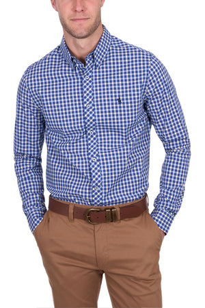 A man models the Thomas Cook James Tailored Shirt, featuring a blue and white check pattern, tucked into tan pants with a brown belt, both hands in his pockets against a white background.