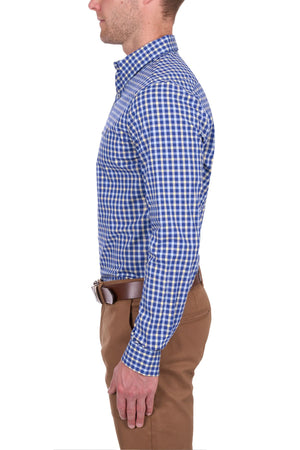A man stands in profile against a white background, wearing the Thomas Cook James Tailored Shirt in blue and white check, tucked into tan pants with a brown belt.