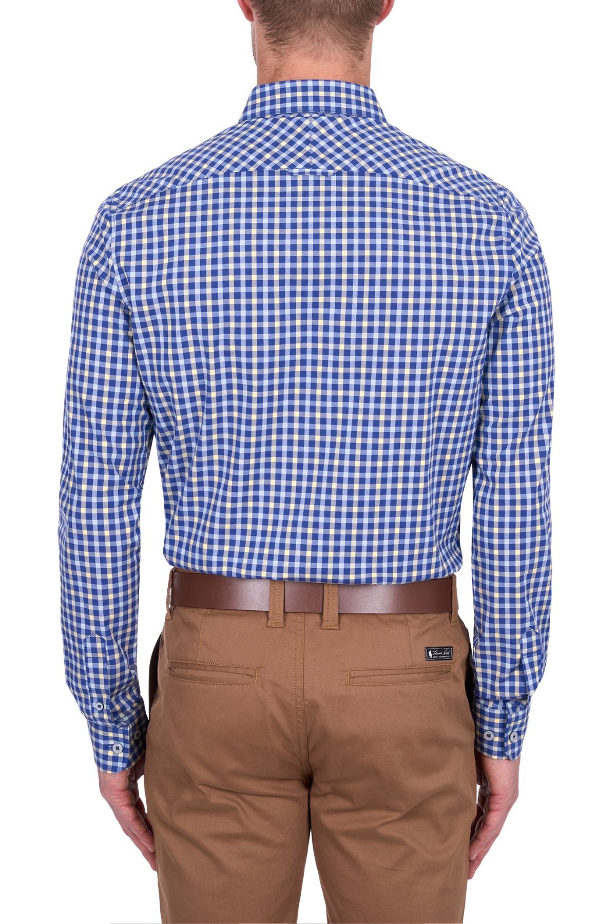 A man is shown from the back wearing the Thomas Cook James Tailored Shirt, a blue and white checkered easy-care dress shirt tucked into tan dress pants with a brown belt.
