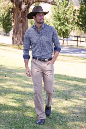 A man in the Thomas Cook Jason Tailored Shirt walks on park grass, smiling and looking to the side, with trees in the background.