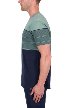 A man stands in profile wearing the Thomas Cook Jason Tee, a 100% cotton jersey with multi-colour stripes in green and navy on the upper half and solid navy on the lower half.