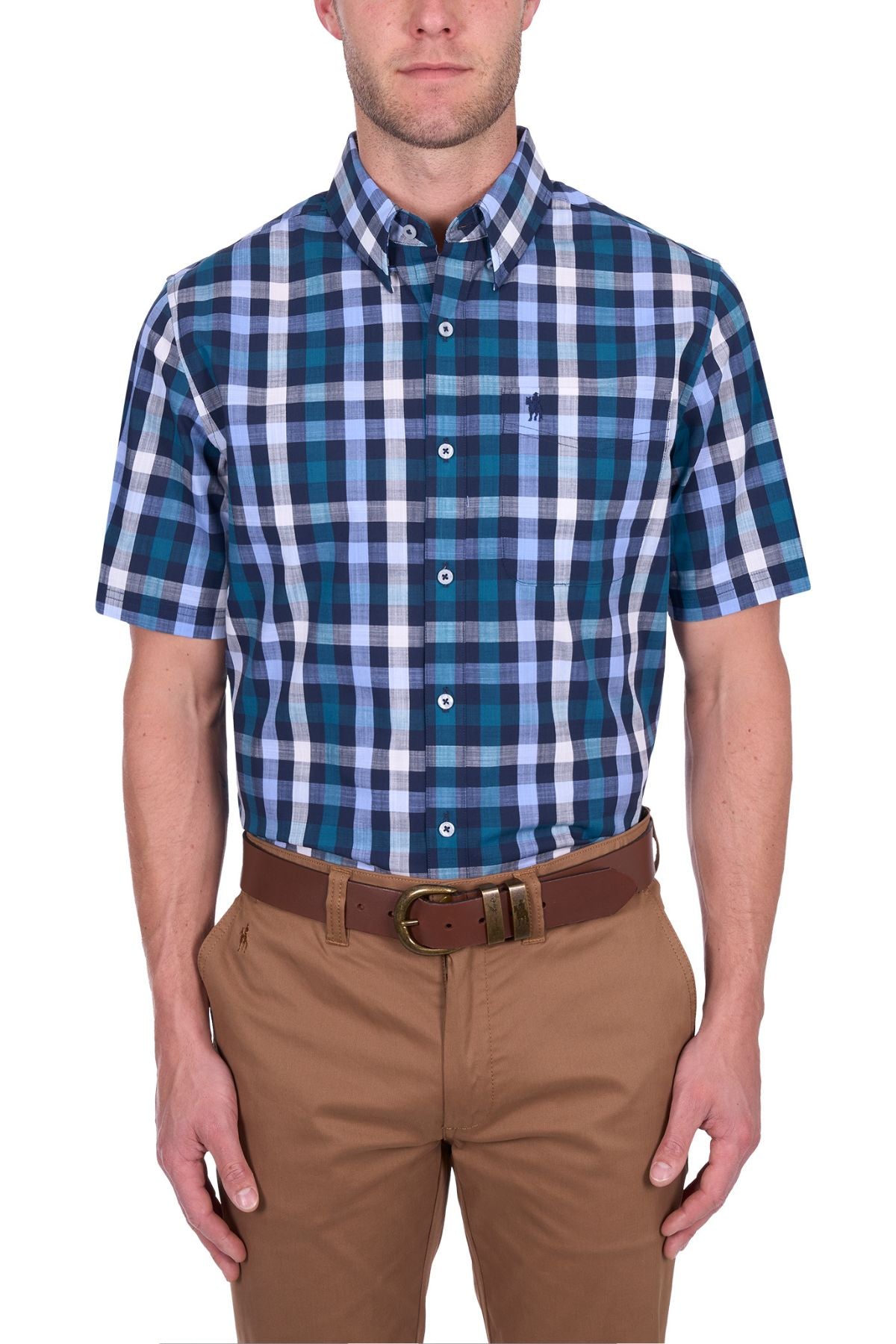 A man wears the Thomas Cook John Short Sleeve Shirt in blue, teal, and white cotton checks, buttoned up and tucked into tan pants with a brown belt, standing against a white background.