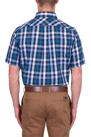 A man is seen from the back wearing the Thomas Cook John Short Sleeve Shirt in a blue, green, and white cotton check pattern, tucked into khaki pants with a brown belt.