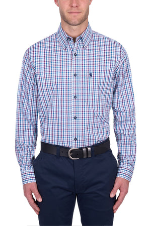 A man wears the Thomas Cook Joseph Shirt, a long-sleeve, blue/red/white plaid 100% cotton button-up, with navy pants and a black belt, standing against a white background.