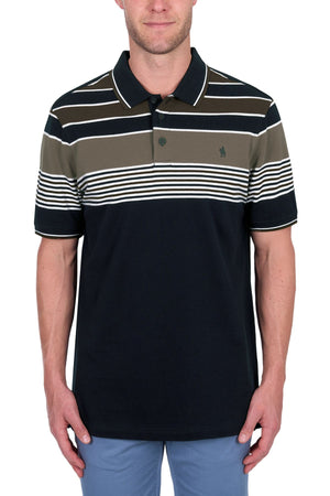 A man wears the Thomas Cook Josua Polo, a 100% cotton pique shirt featuring white, brown, and olive green stripes above solid black, paired with light blue pants.