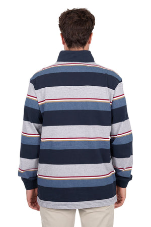 A person with short brown hair is facing away from the camera, wearing the Thomas Cook Nathan 1/4 Zip Rugby featuring wide navy, gray, white, and red stripes, paired with light-colored pants.