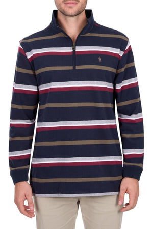 A man wears the Thomas Cook Nicholas 1/4 Zip Rugby—a heavyweight, long-sleeve jersey with navy, burgundy, white, and olive green stripes and a small embroidered logo on the left chest—paired with beige pants.