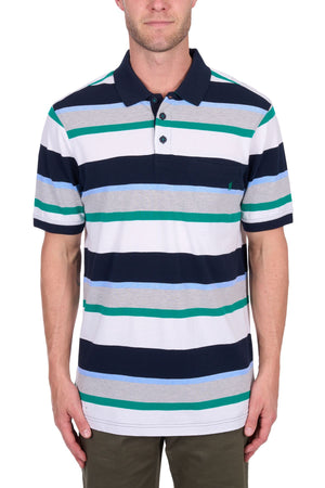 A man wears the Thomas Cook Paul Polo, a short-sleeve cotton pique shirt with navy, white, gray, green, and blue stripes. It features a collar and neck buttons and he stands with his arms relaxed at his sides.
