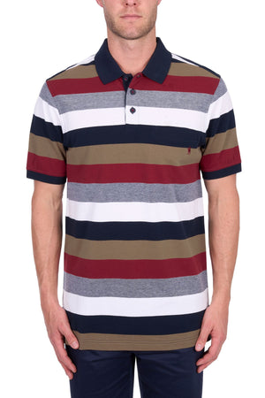 A man wears the Thomas Cook Sean Polo, featuring navy, white, red, grey, and olive green stripes in cotton pique fabric, paired with navy blue pants against a plain white background.