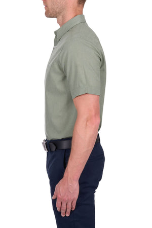 A man in profile wears the Thomas Cook TC Linen Short Sleeve Shirt in light green with navy pants and a black belt against a white background—a true summer essential.