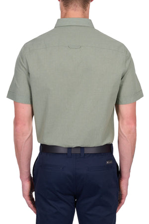 A man is shown from the back, wearing a Thomas Cook TC Linen Short Sleeve Shirt in light olive green and dark navy blue pants, standing against a white background.