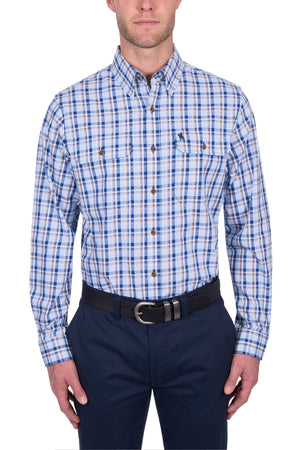 A man wearing a blue, white, and tan Thomas Cook Thomas Shirt with long sleeves, dark blue pants, and a black belt stands against a white background.