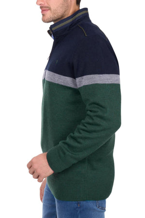 A man wearing the Thomas Cook Troy 1/4 Zip Jumper in a green, navy blue, and gray color-block design stands sideways with his left hand near his waist, paired with blue jeans.