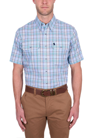 A man wearing the Thomas Cook Matt Short Sleeve Shirt in blue, green, and white plaid, tucked into tan pants with a brown belt, stands against a white background.