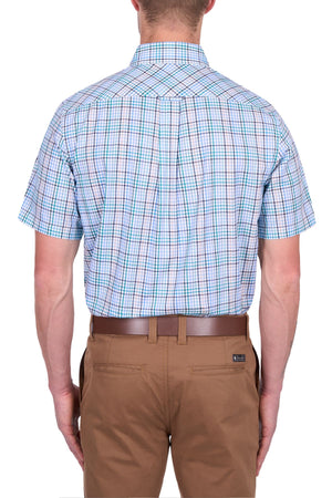 A man seen from the back wears a Thomas Cook Matt Short Sleeve Shirt in blue plaid with tan dress pants and a brown belt, set against a white background.