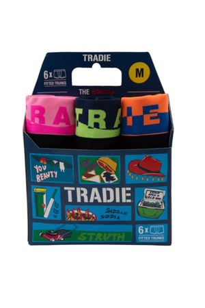 A box of Tradie Mens 6PK Trunk, size M, includes six cotton trunks in assorted bright colors with bold graphics, Aussie slang, and cartoon-style packaging—classic men's underwear with a fun twist.