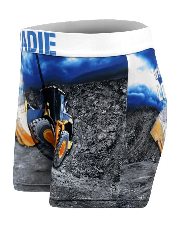 The Tradie Mens Work N Surf Trunk features a yellow construction loader print on rocky terrain with a blue sky, a white waistband, and quick-drying fabric for cool comfort all day—perfect for work or play.