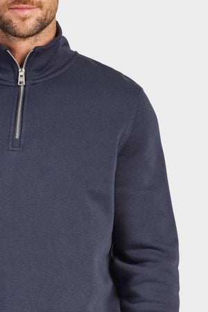 Model wears the Academy Brand 1/4 Zip Sweat in navy, cut from premium brushed fleece. Only the lower face, neck, and upper torso are shown against a light gray background.