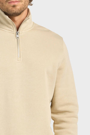 A person wears the Academy Brand 1/4 Zip Sweat in light beige with a vintage washed finish, zipper partially up. Only their lower face and upper torso are shown against a plain light background.