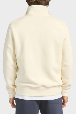 A person shown from the back wears the Academy Brand 1/4 Zip Sweat in cream over a white shirt with dark pants, highlighting its premium brushed fleece, high collar, and subtle vintage style.