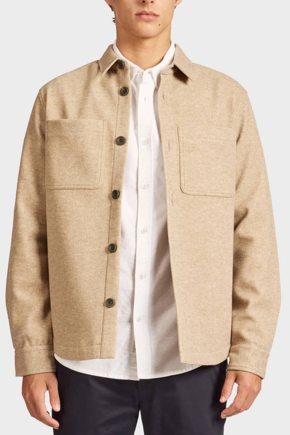 Wearing the Academy Brand Lloyd Overshirt—a tan men's overshirt with two chest pockets—layered over a white collared shirt and dark pants, shown from shoulders to mid-thigh against a plain backdrop.