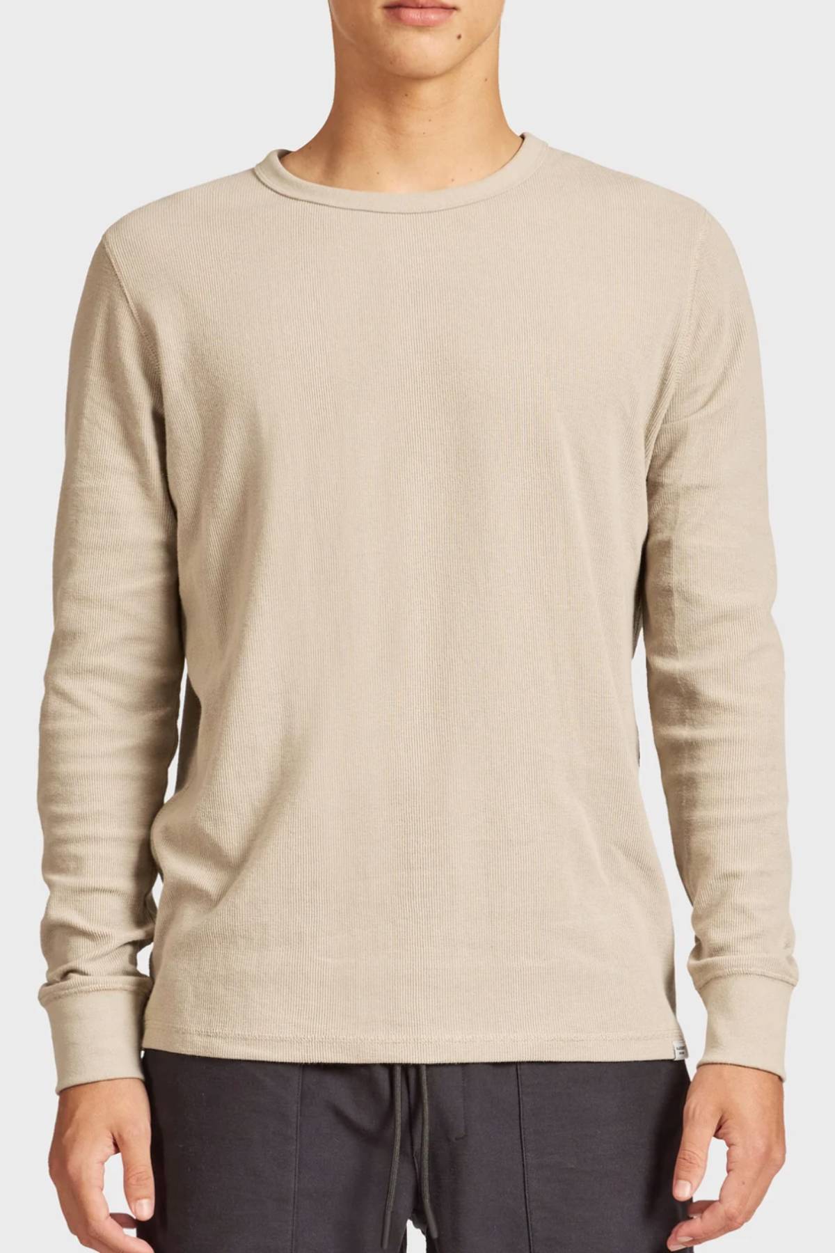 A person wearing the Academy Brand Workers Crew in beige with dark pants stands facing forward against a plain light background.