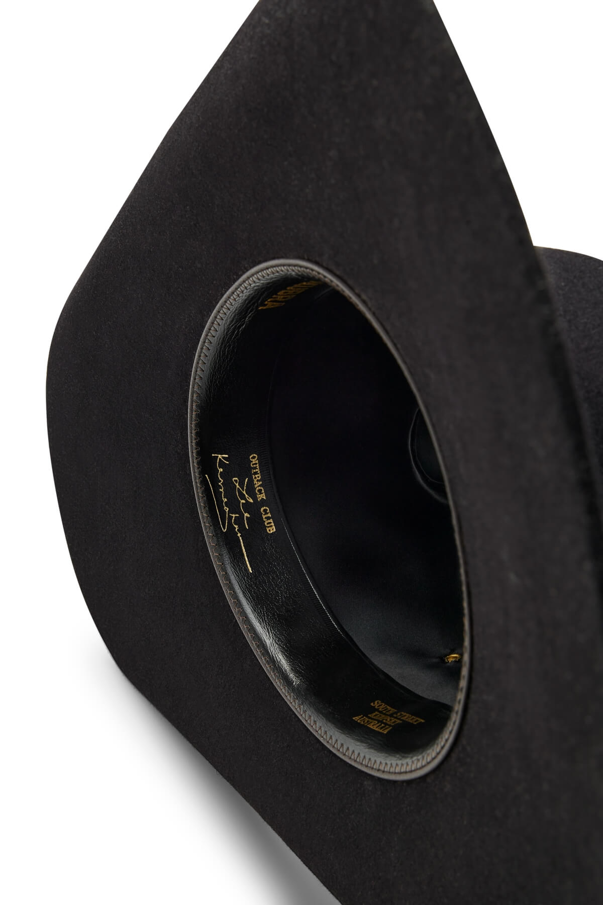 A close-up of the inside of a black Akubra Outback Club hat, featuring gold lettering and Australian country star Lee Kernaghan’s signature along the inner band.