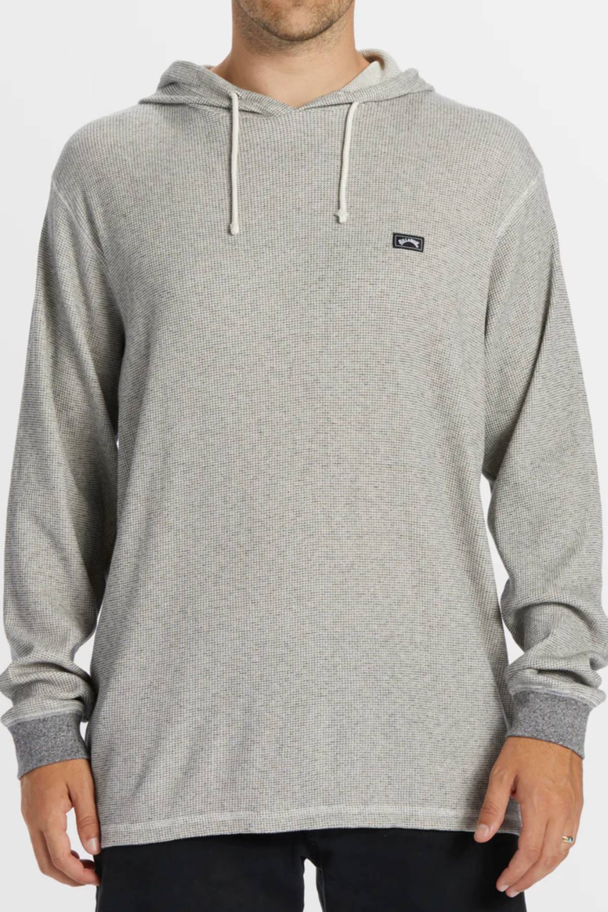 A person wearing the Billabong Keystone Pullover, a light gray long-sleeve hoodie with white drawstrings and a small rectangular logo on the left chest, stands against a plain background.