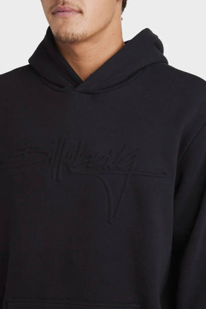 A person wears the Billabong Tonal Boss Pop Hood in black, featuring subtle embossed front text. The image shows them from shoulders to upper chest with a partially visible face.