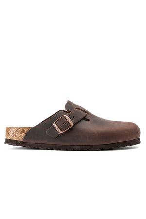 The Birkenstock Boston is a brown, closed-toe slip-on clog with an adjustable buckle, anatomically shaped footbed, and black rubber sole, shown from the side for classic comfort.